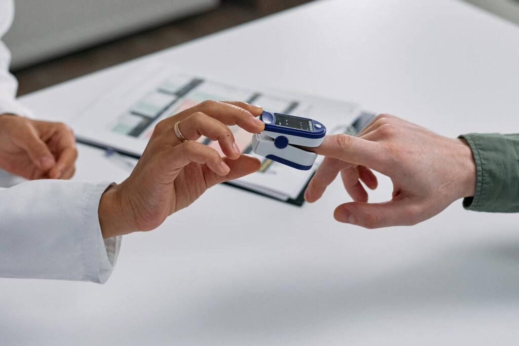 Close-up of a fingertip pulse oximeter being used to measure a patient's heart rate and oxygen levels.