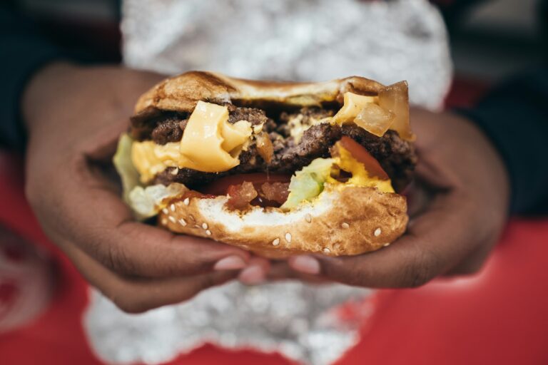 telling Cholesterol myth vs fact with a cheese burger in hand